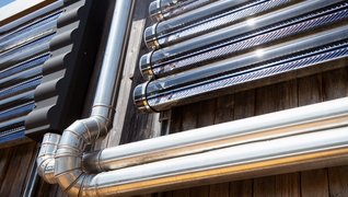 Les capteurs solaires thermiques tubulaires sur la façade de la maison individuelle située à Villars-sur-Glâne (FR) fournissent l'énergie nécessaire pour le chauffage des locaux et la préparation.